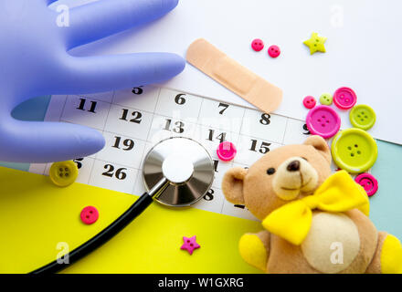 Children`s doctor appointment date number concept. Calendar with numbers, doctor, kids toys, pink and green buttons. Flat lay view. Stock Photo